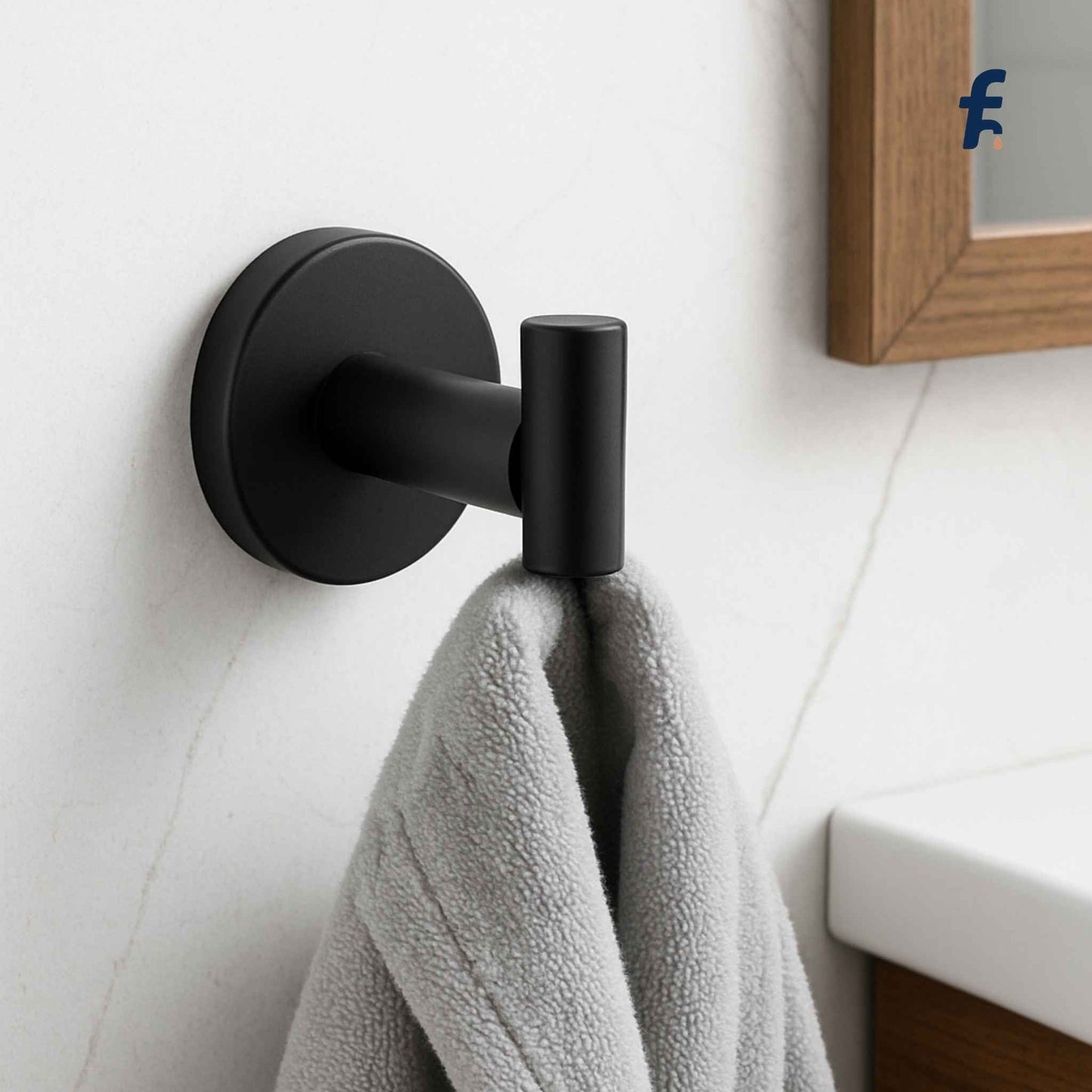 Black towel hook with a gray towel on a white wall. Black brass wall-mounted napkin ring holder in premium brass finish for modern luxury bathrooms