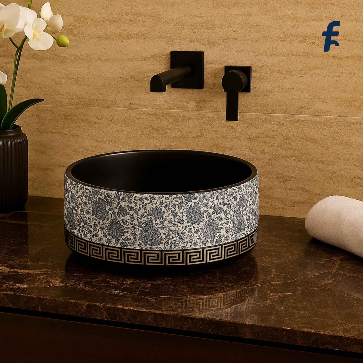 Decorative bathroom sink with black and white pattern on a marble countertop, with a beige tiled wall and orchid plant in the background.