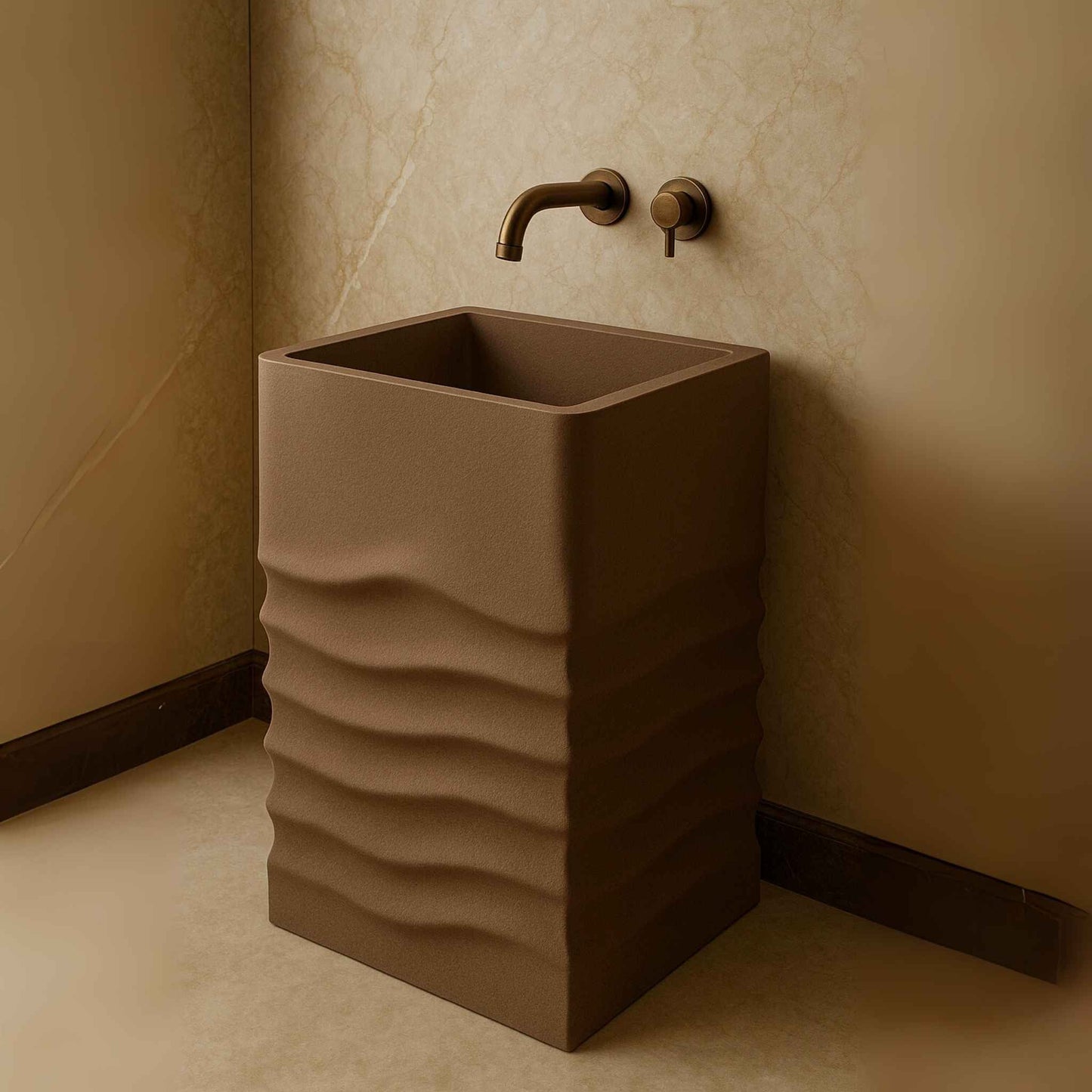 Side angle of a taupe textured pedestal washbasin with wall-mounted antique brass faucet in a beige marble luxury bathroom.