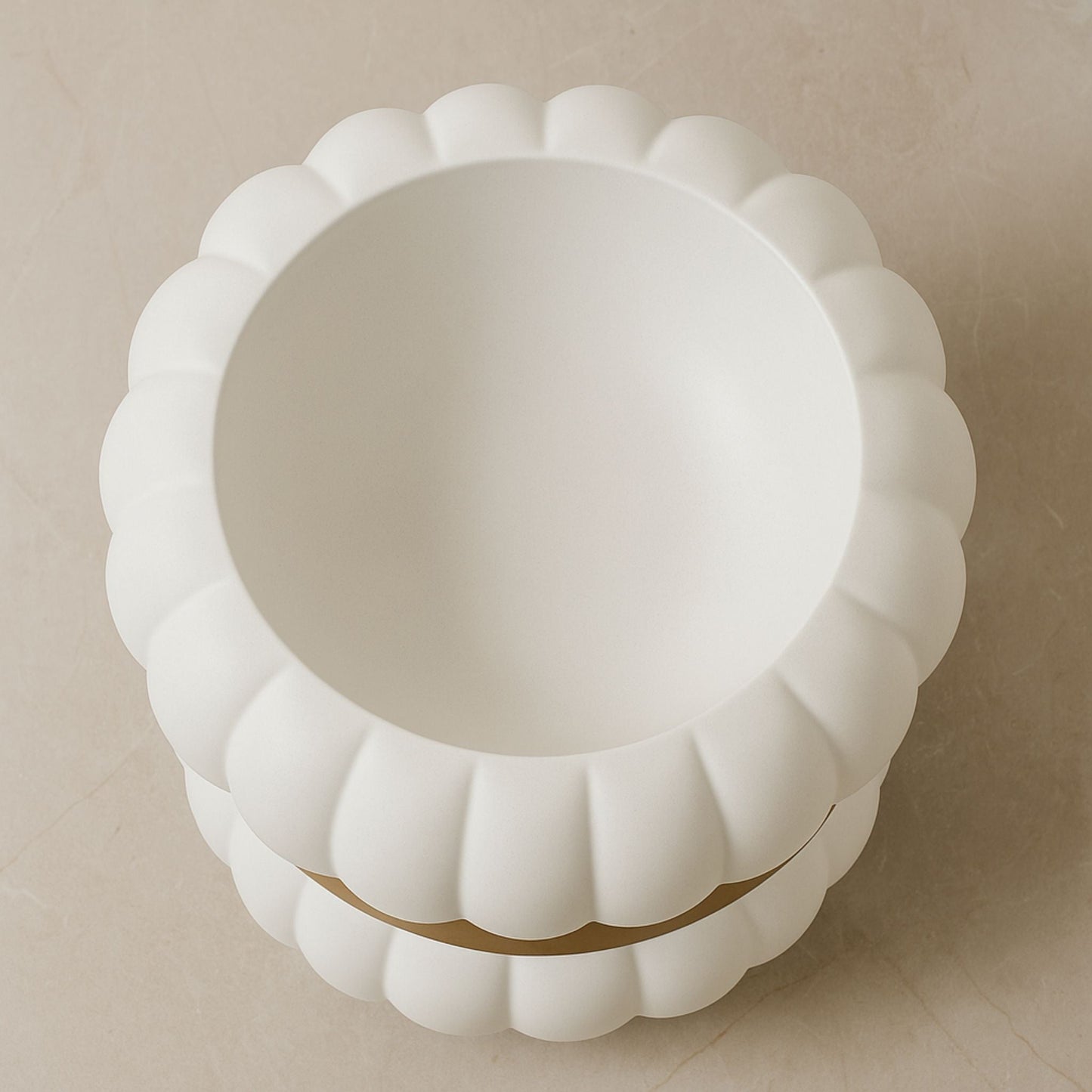 Top-down view of white round fluted basin with gold faucet