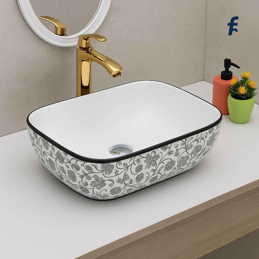 Bathroom vanity with floral-patterned sink, gold faucet, and decorative items.