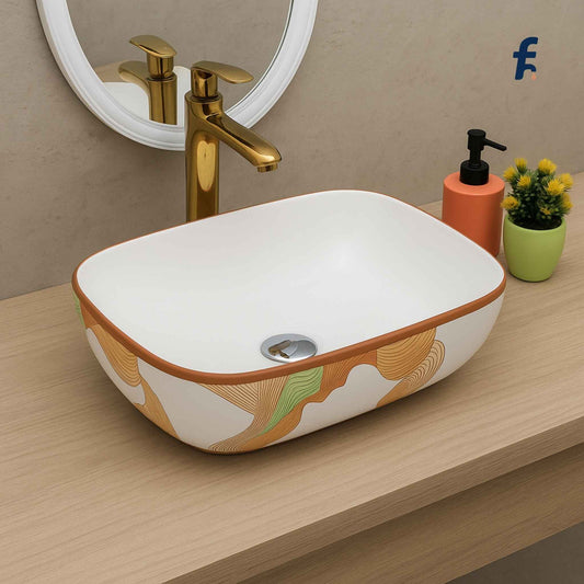 Bathroom sink with decorative patterns, gold faucet, and small plant on a wooden counter.