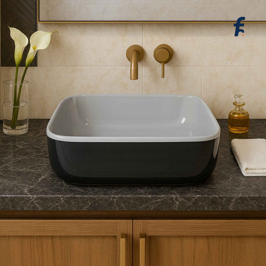 Bathroom sink with black and white basin, gold faucet, and decorative elements.