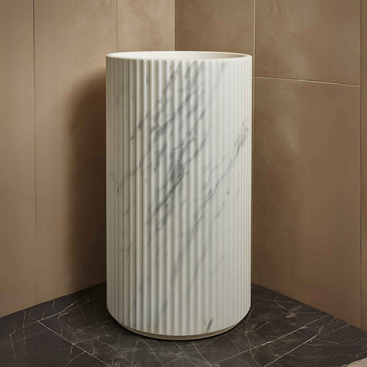 Front view of white marble fluted pedestal sink with floor-mounted tap