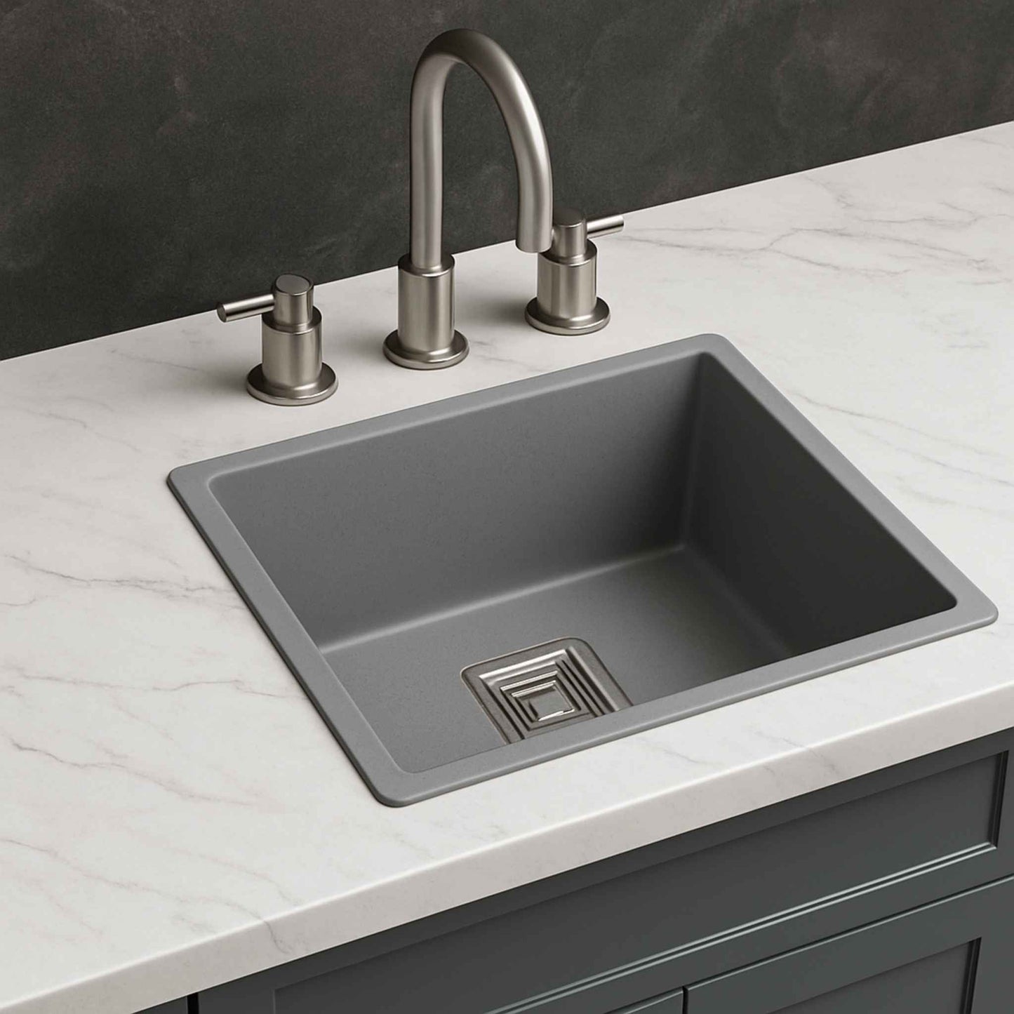 Side view of grey metallic under-mount kitchen sink on light marble countertop with brushed steel faucet