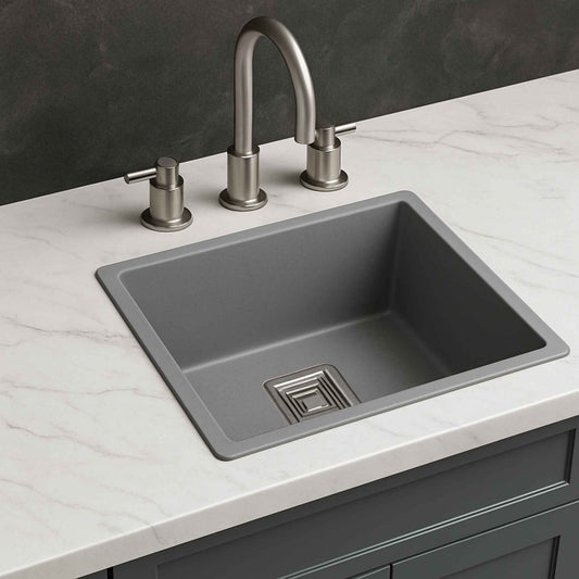 Side view of grey metallic under-mount kitchen sink on light marble countertop with brushed steel faucet
