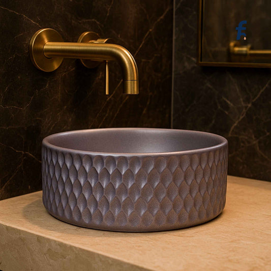  Side angle view of lavender designer ceramic basin placed on beige marble countertop with elegant gold fixtures.