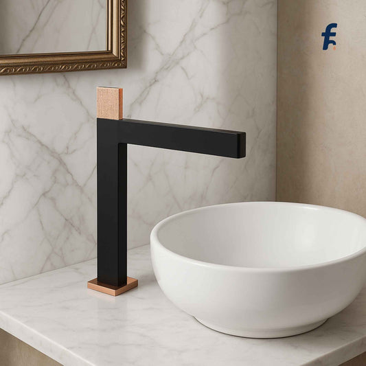 Black faucet with bronze accents on a white sink against a marble wall. Premium brass basin mixer tap with knurled handle in rose gold