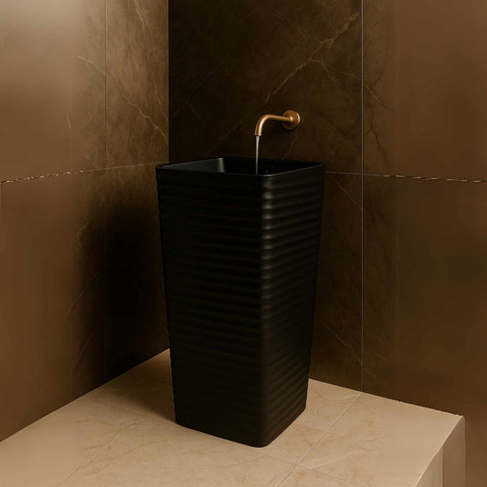 Front view of matte black ripple pedestal washbasin in marble bathroom
