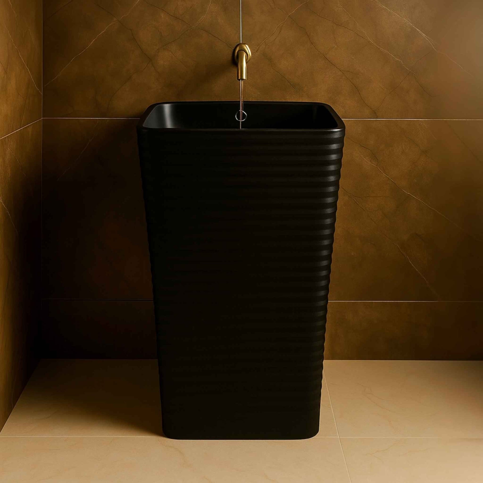 Front view of a matte black freestanding pedestal wash basin with ribbed design and gold faucet in a luxurious modern bathroom.