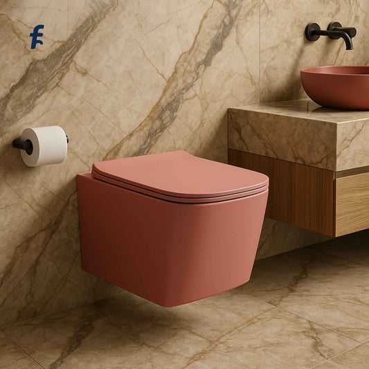 Pink wall-mounted toilet in a bathroom with marble walls and a sink.