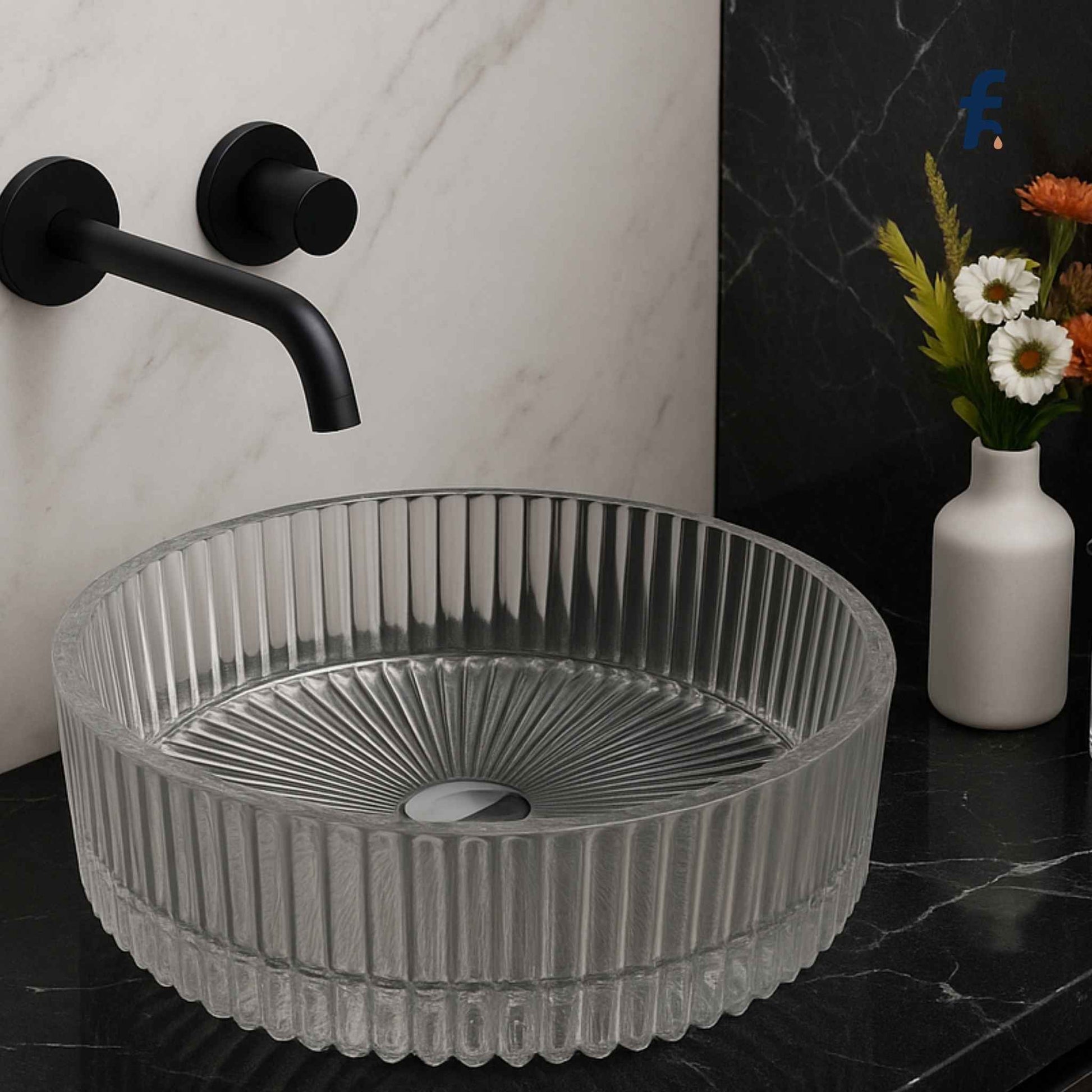 Grey ribbed sink on a black marble countertop with a black faucet and white vase with flowers in the background. Modern bathroom vanity featuring luxury glass washbasin with black faucet.