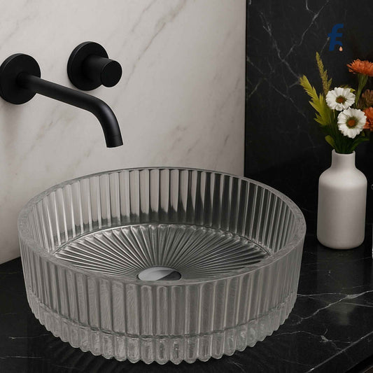 Grey ribbed sink on a black marble countertop with a black faucet and white vase with flowers in the background. Modern bathroom vanity featuring luxury glass washbasin with black faucet.