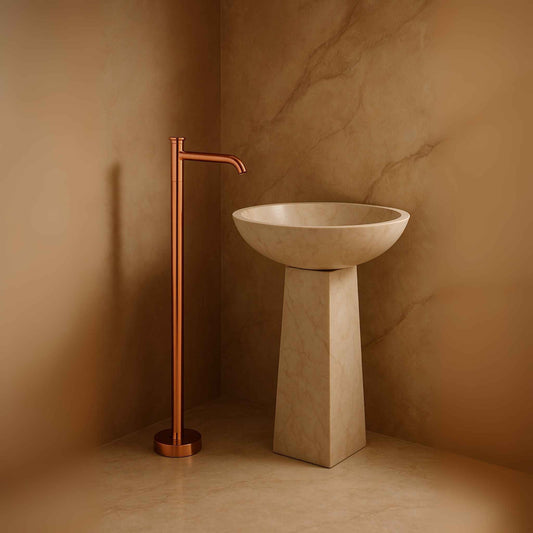 Rose gold floor mounted basin mixer beside luxury round pedestal in elegant bathroom