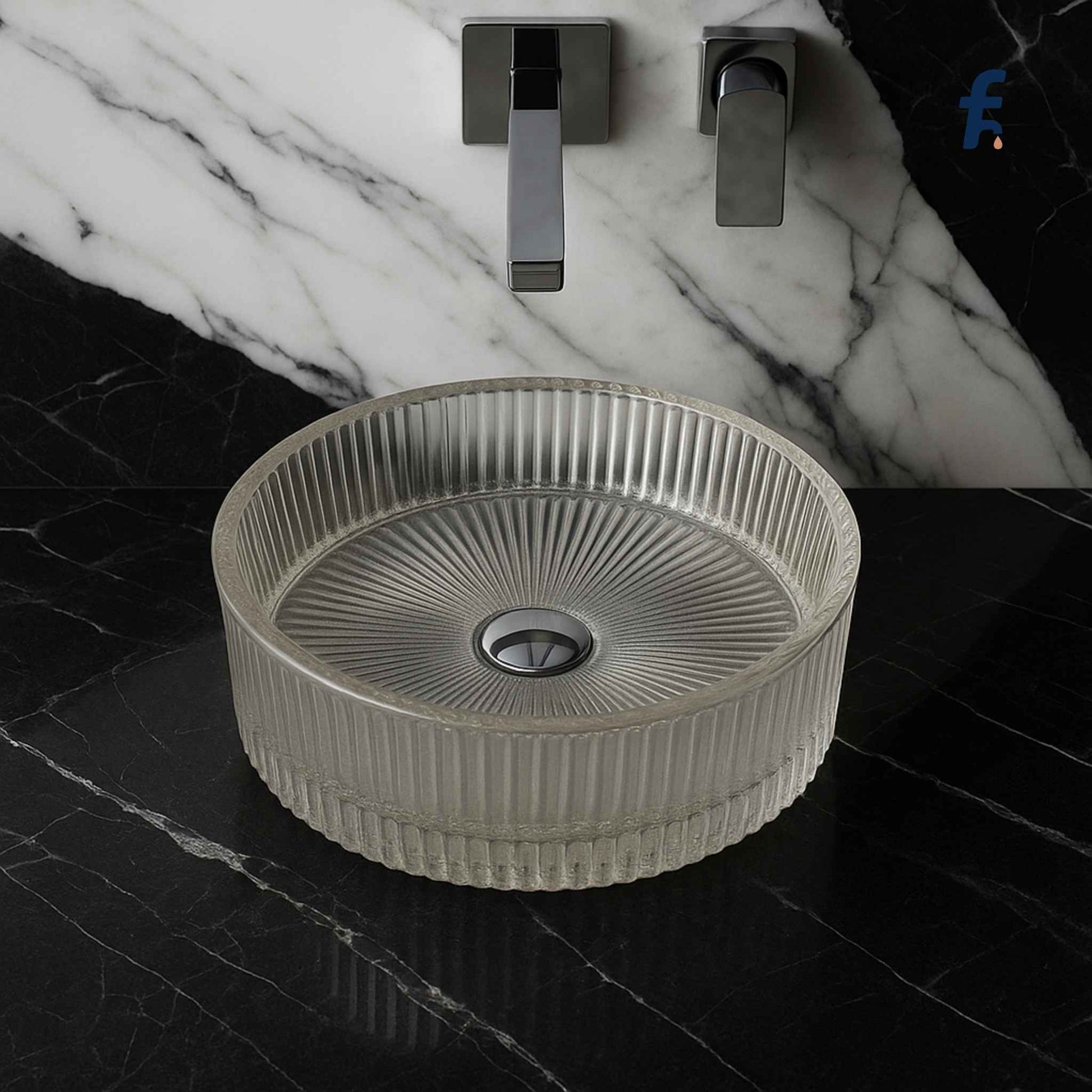 Round ribbed sink on a black tiled bathroom floor with marble wall and faucet. Top angle view of round fluted glass washbasin on marble vanity.