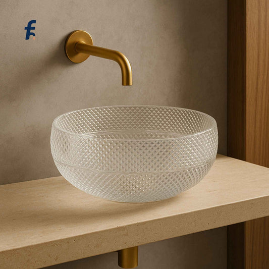 Glass sink with textured design on a wooden countertop, gold faucet against a beige wall.