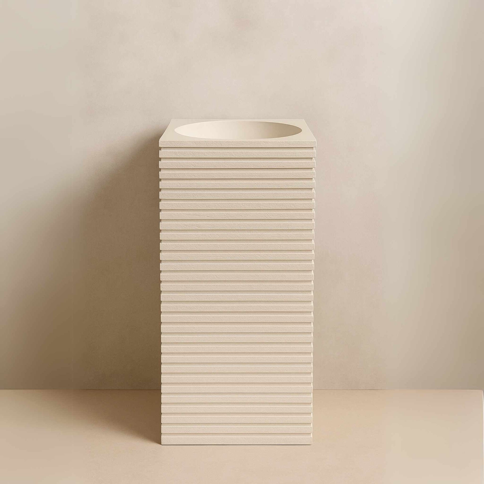 Front view of textured off-white pedestal basin with stacked design