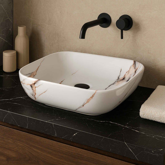 Front view of rectangular white marble wash basin with copper and grey veining on black stone vanity