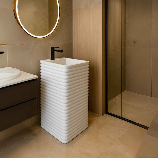 White ribbed pedestal basin in luxurious modern bathroom with LED mirror and shower